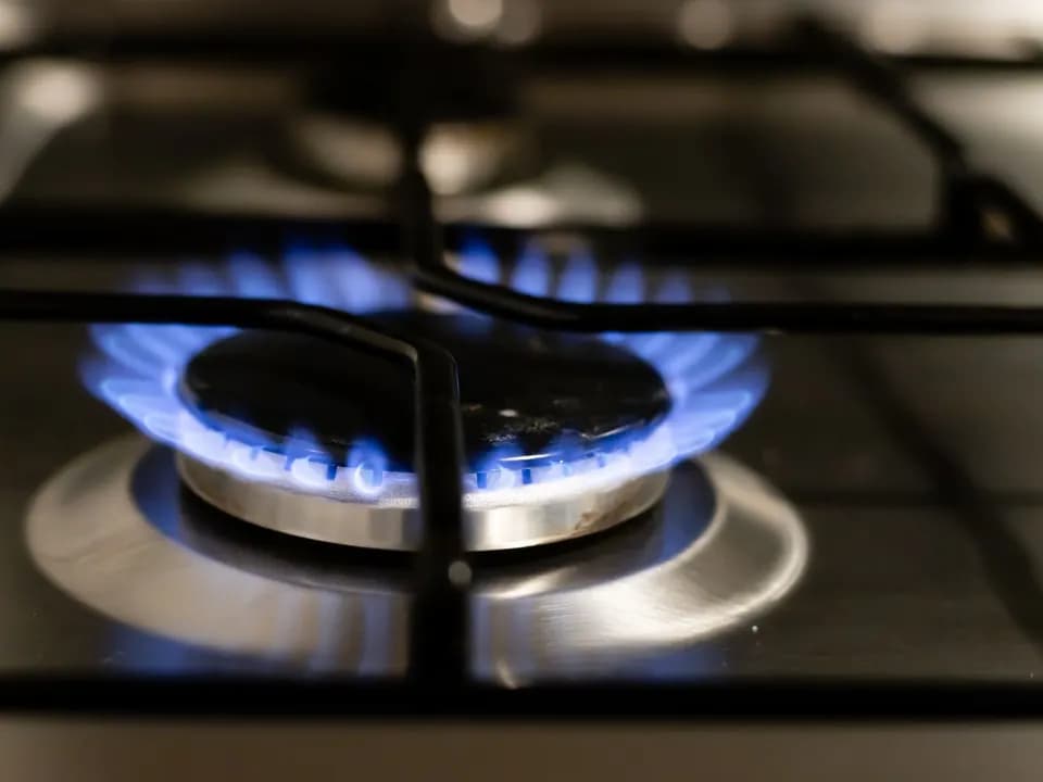 Ocak ızgarasının altında mavi alevle yanan gaz brülörü